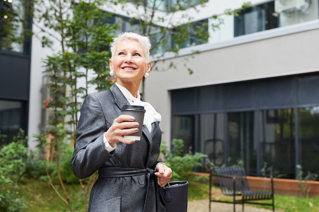 Mature businesswoman with coffee outdoors