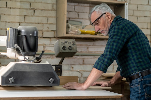 Mature carpenter working on worrdworking equipment