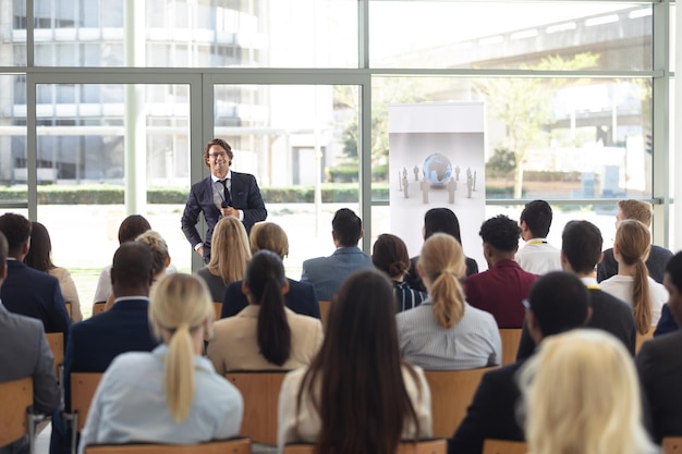 Mature Caucasian male executive doing speech in conference room answering question