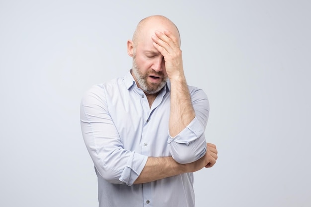 Mature caucasian man having headache feeling tired after hard day