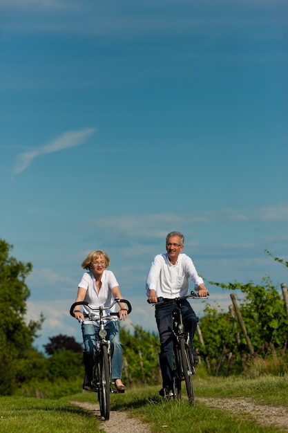 Mature couple cycling on rural road in summer