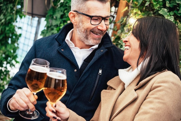 Mature couple having fun drinking beer at cafe bar restaurant