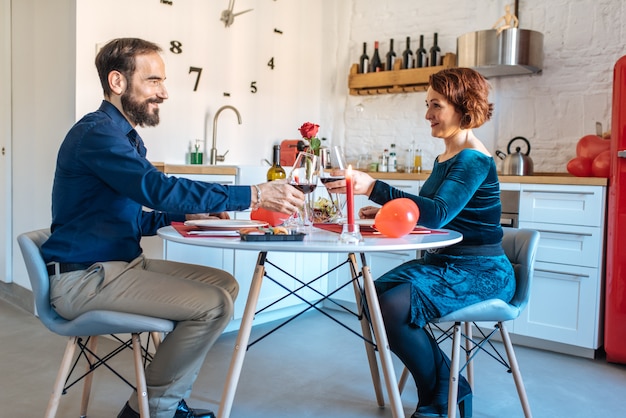 Mature couple having a romantic dinner at home for valentines day and doing toast with red wine 
