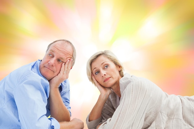 Mature couple lying and thinking against girly pink and yellow pattern