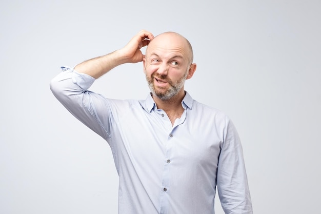 Mature european bearded young male dressed in casual white shirt trying to remember where he put the car keys