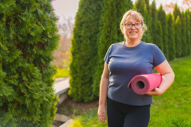 Mature Female On Outdoor Yoga Retreat Walking Along Path Through Campsite