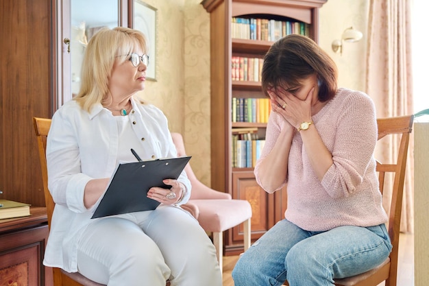 Mature female psychologist counseling a middle aged woman