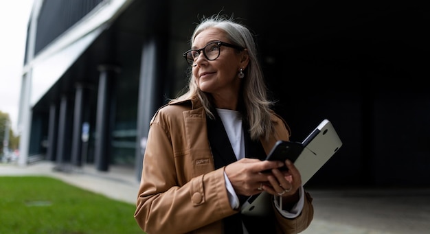 Mature grayhaired businesswoman with a laptop in her hands on the background of the business center