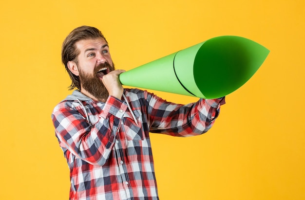 Mature handsome man in checkered shirt speak in paper loudspeaker, ad.