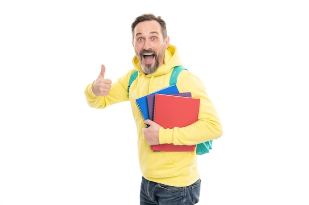 Mature happy man carry backpack and notebook. smiling senior guy back to school isolated on white. caucasian man in yellow hoody planning his work. literature education for adult. guy hold workbook.