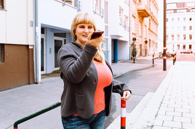 Mature happy middle aged woman, 40s, with long blond hair, smiling, wearing jeans and knitted jacket