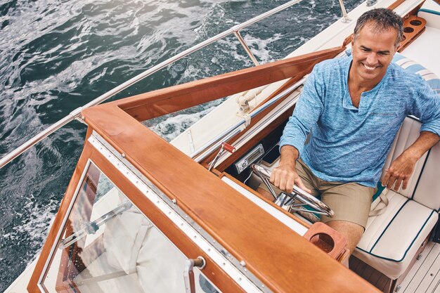 Photo mature man boat and smile in water for retirement leisure and investment for travel luxury happiness and male sailor on tropical coast with adventure yacht and transport on ocean with high angle