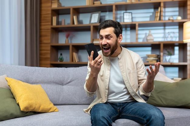 Mature man celebrating victory and successful achievement got news online message on app using phone