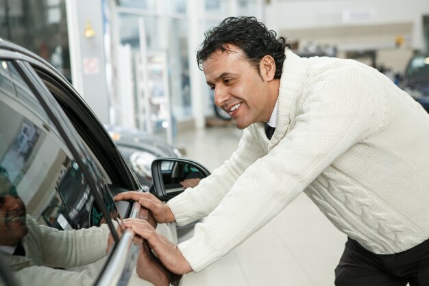 Mature man choosing a new car at the dealership salon