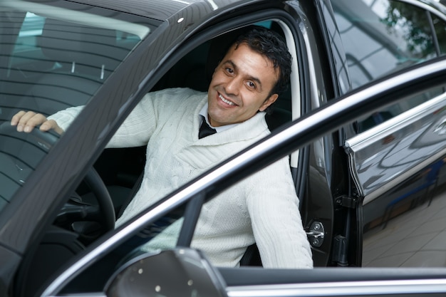 Mature man choosing a new car at the dealership salon