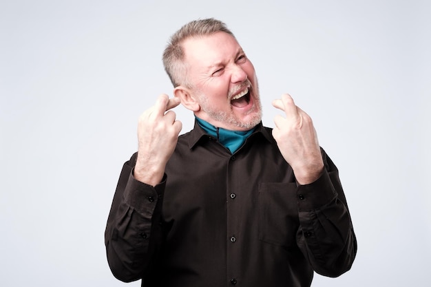 Mature man crosses his fingers making a wish