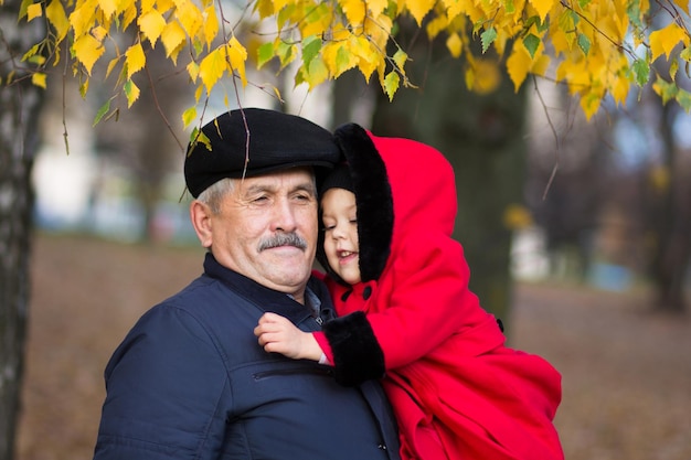 Mature man holding on hands little girl outside