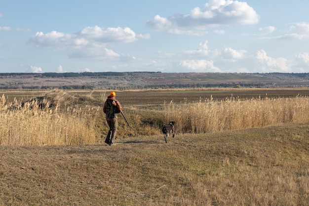 Photo mature man hunter with gun while walking on field