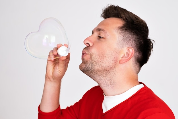 A mature man inflates soap bubbles like a child