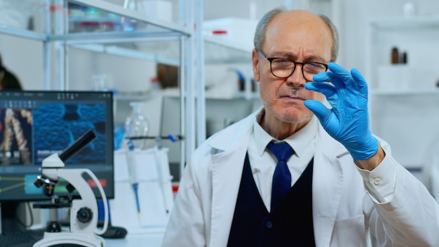 Photo mature man lab technician looking at virus sample in modern equipped laboratory. scientist working with various bacteria tissue and blood tests, concept of pharmaceutical research for antibiotics