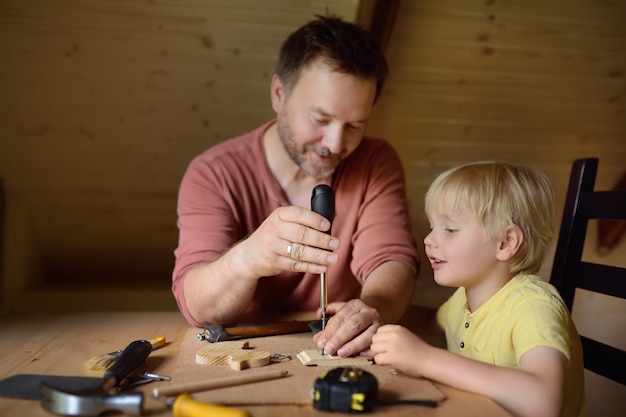 Mature man and little boy make a wooden toy together. 