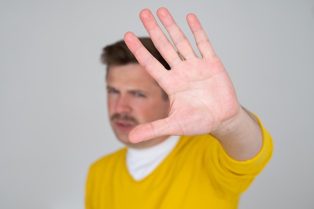 Mature man looking serious showing open palm making stop gesture