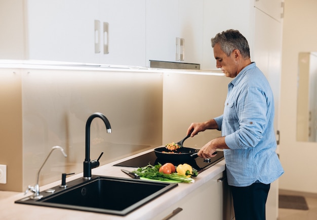 Mature man preparing healthy food for dinner for his family