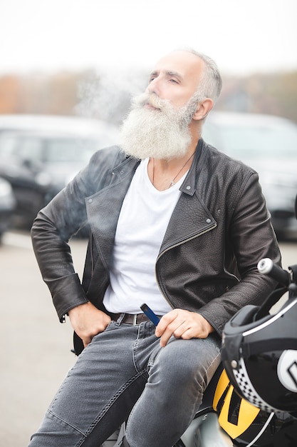 Mature man riding a motorcycle. Old male on motorbike. Bearded man outdoors driving.