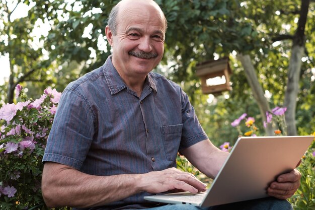 Mature man sitting in garden in countryside with notebook and relaxing