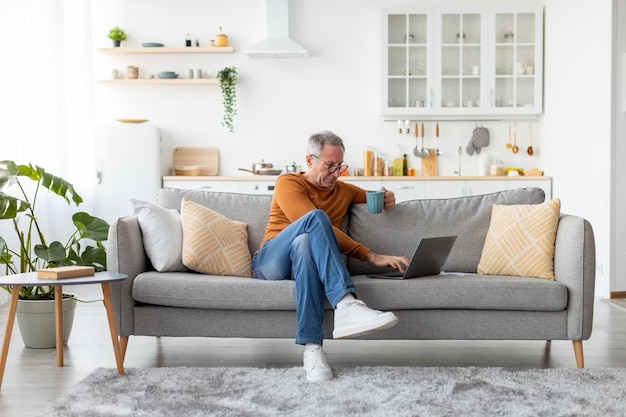 Mature man watching video on computer drinking coffee