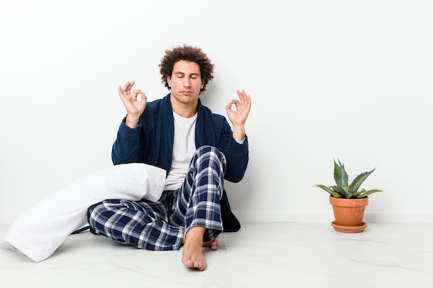 Photo mature man wearing pajama sitting on house floor relaxes after hard working day