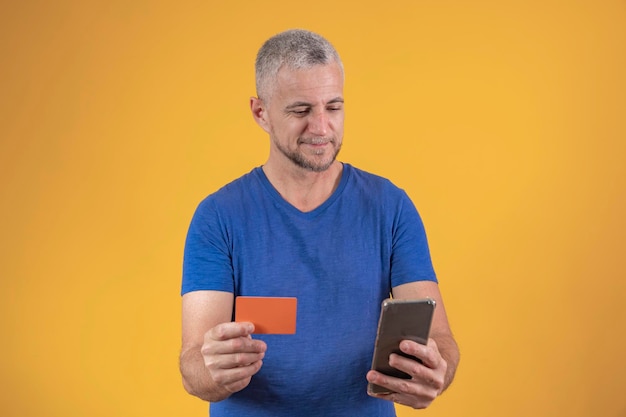 Mature man with a credit card in his hands shopping by cell phone online