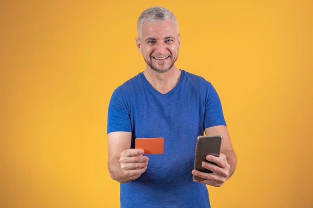 Mature man with a credit card in his hands shopping by cell phone online