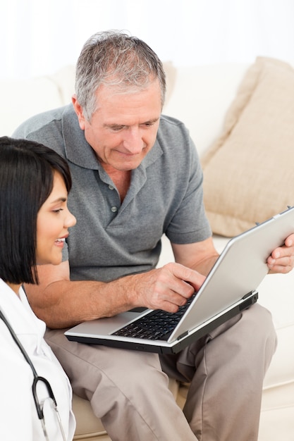 Mature man with his nurse looking at the laptop at home