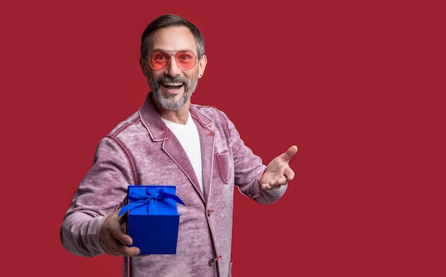 Mature man with present isolated on red background with copy space stylish man hold present