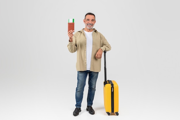 Mature man with suitcase and passport ready to travel