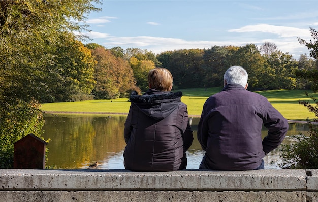 Mature man and woman sitting on a city park bench Landscape in winter background