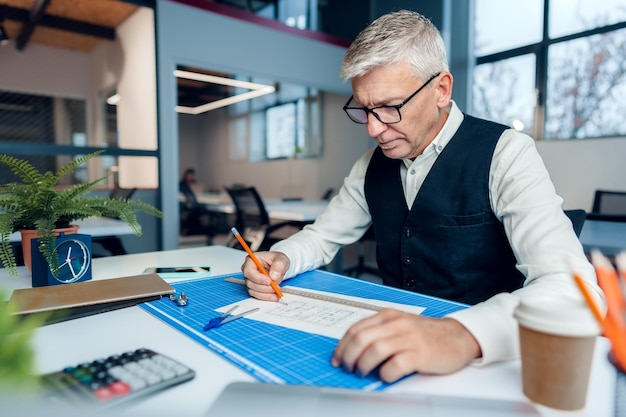 Mature man working on architectural project in office