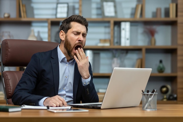 Mature man yawning inside classic office senior businessman in workplace sleepless and overworked