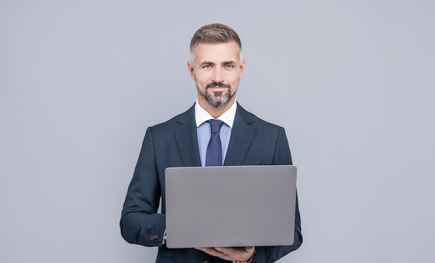 Mature manager with grizzled hair in formal suit working on computer online freelancer