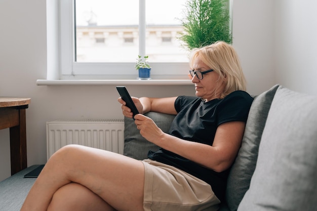 Mature middle age woman dealing ebook at home on the couch