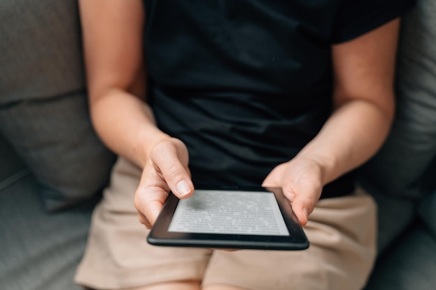 Mature middle age woman dealing ebook at home on the couch