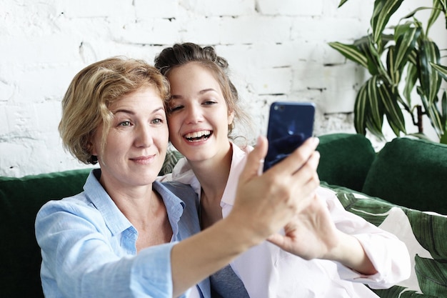 Photo mature mother and her daughter making a selfie using smart phone lifestyle concept