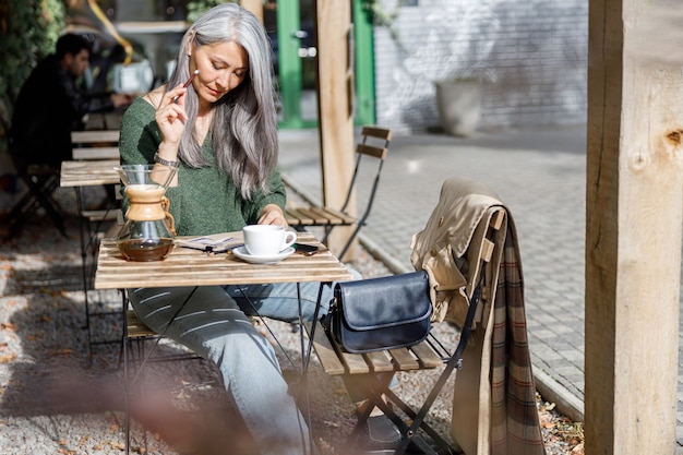 Mature pale hair stylish woman lifestyle portrait outdoors near cafe