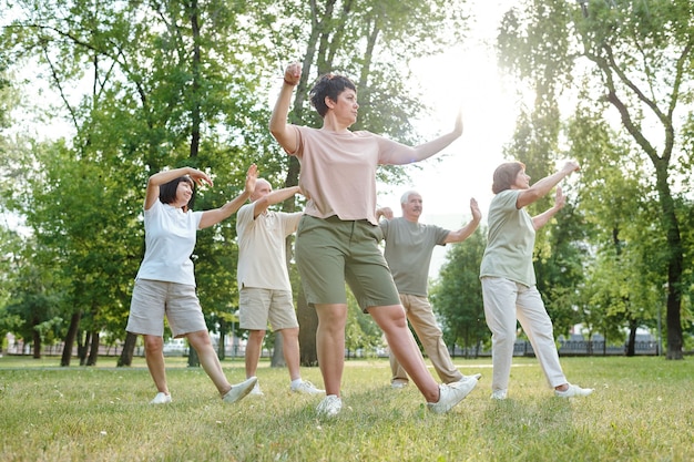 Mature people practicing together with instructor in the park outdoors