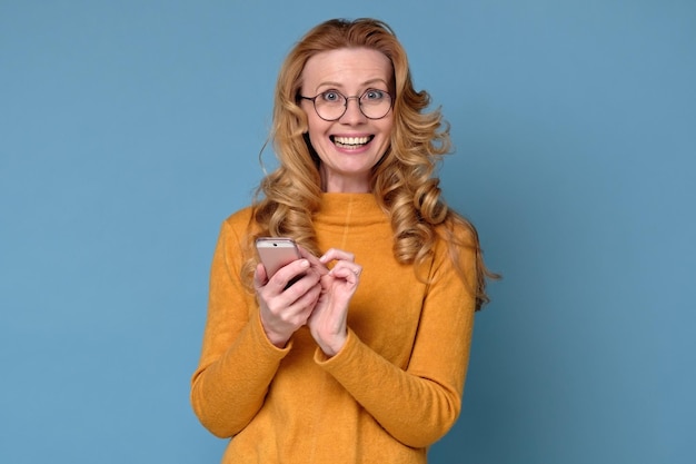 Mature pretty woman smiling as she reads a text message on her smartphone