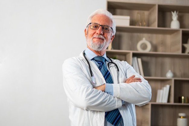 Mature senior male doctor in glasses medical uniform smiling looking at camera in hospital or doctor