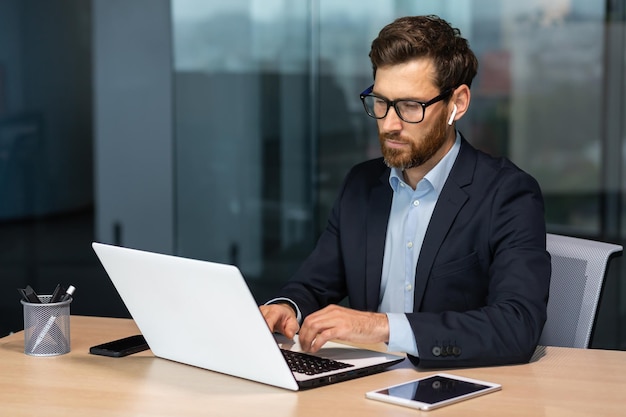 Mature serious businessman working inside modern office building senior boss in business suit typing