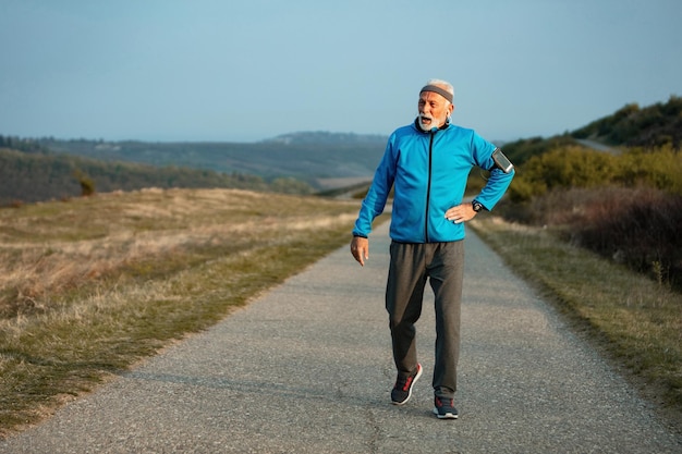 Mature sportsman feeling tired after running and taking a walk on the road in nature Copy space