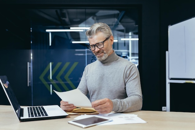 Mature successful gray haired businessman smiling and happy received letter notification senior male